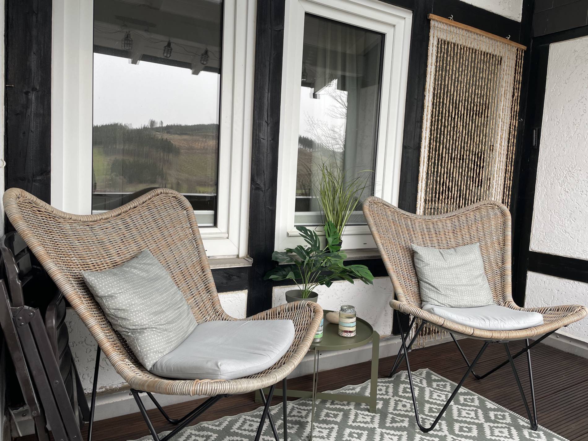 Korbsessel auf dem Balkon mit Kissen und Talblick